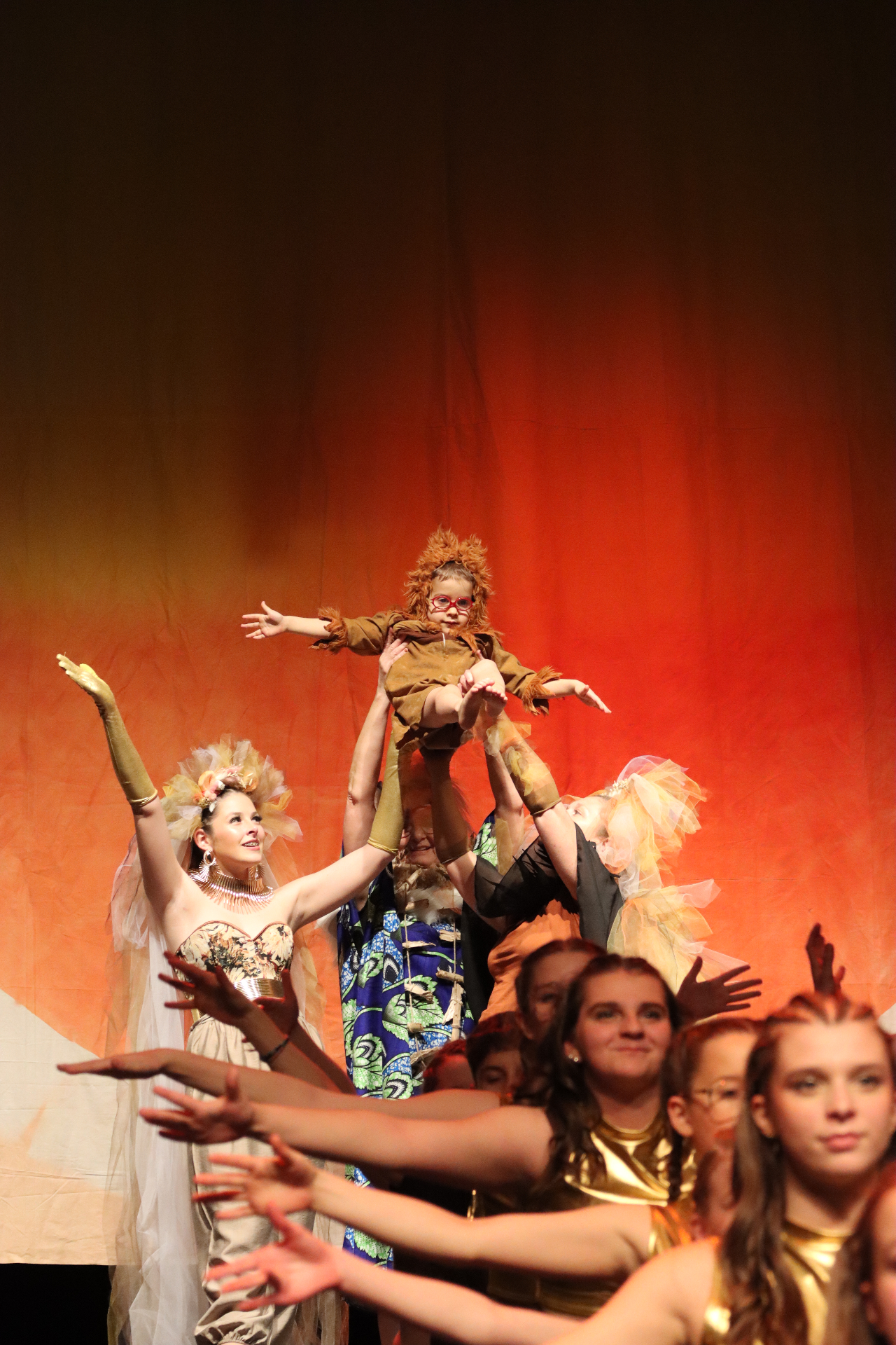 Troupe de danseuses portant un enfant costumé en lionceau, spectacle Roi Lion