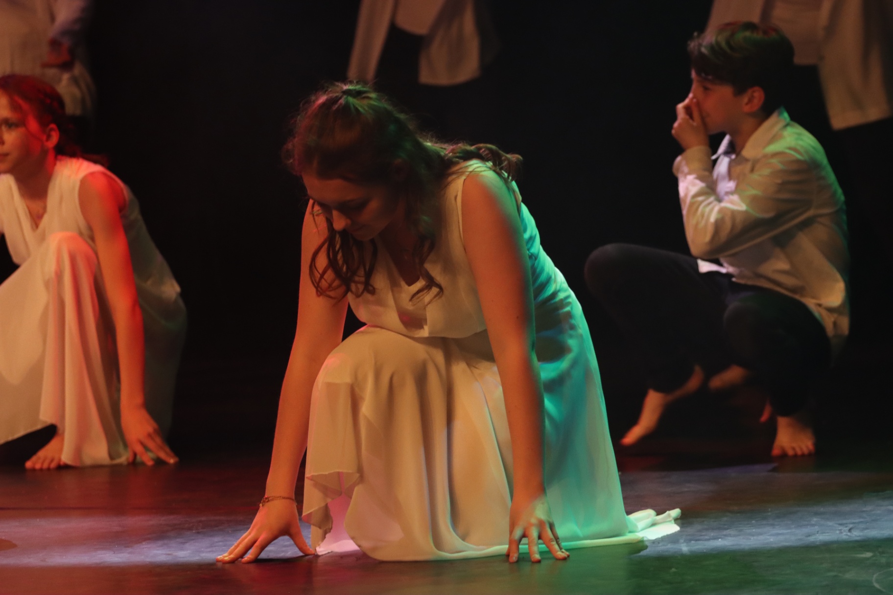 Danseuse en robe blanche vaporeuse agenouillée sur scène